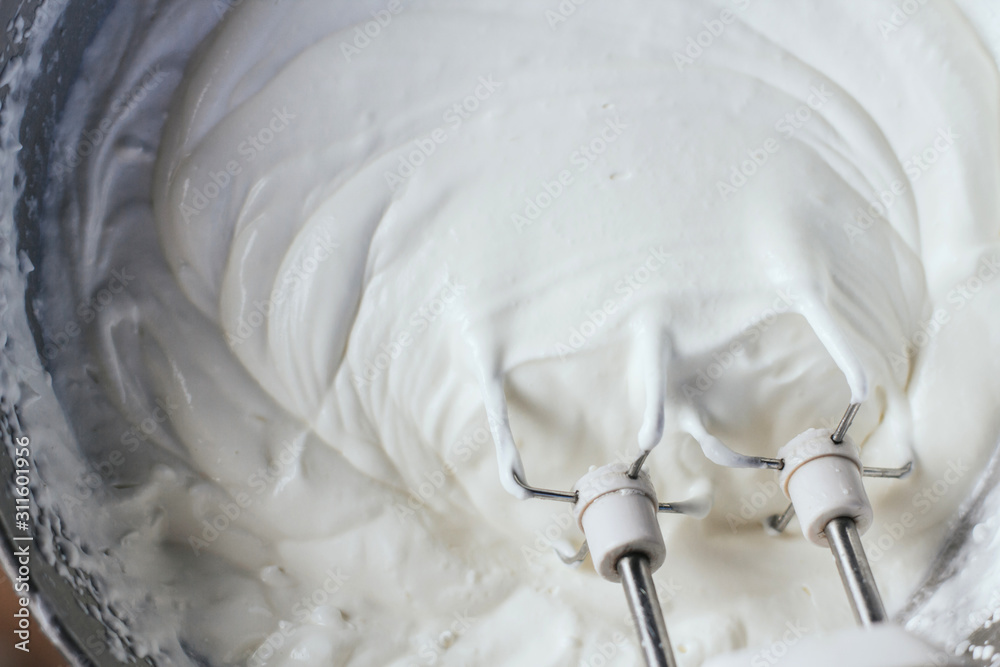 Beating a white cream with a mixer in a metal bowl. Whipped cream. Cream  for the cake Stock Photo - Alamy