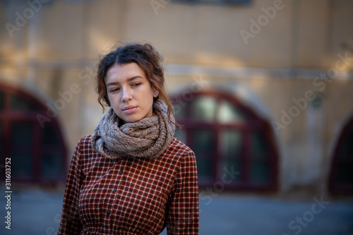 Dreaming young woman with spectacular curly red ginger hair looking at camera posing outdoor in downtown street. Female portrait.