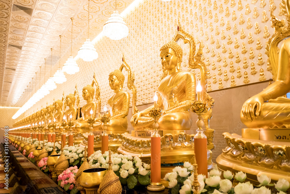 Fototapeta premium Thai Golden Buddha statue. Row of golden buddha statue. Thai Golden Buddha statue. Buddha image in the middle. Statue of Buddha sitting in meditation.