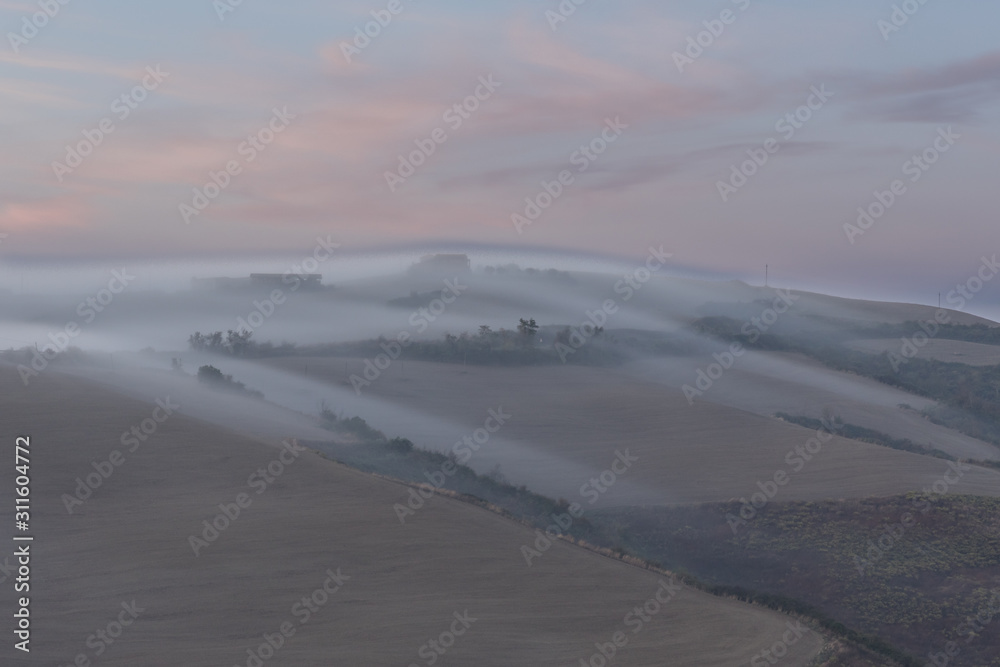 Morning fog rolling over Tuscan hils in Italy