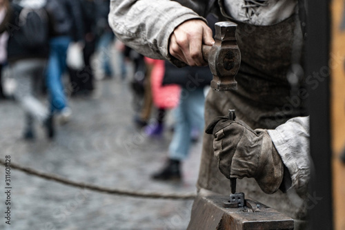 Blacksmith working on metal on anvil at forge