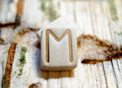 Wooden rune Ehwaz close-up on a wooden background. Soft focus photo