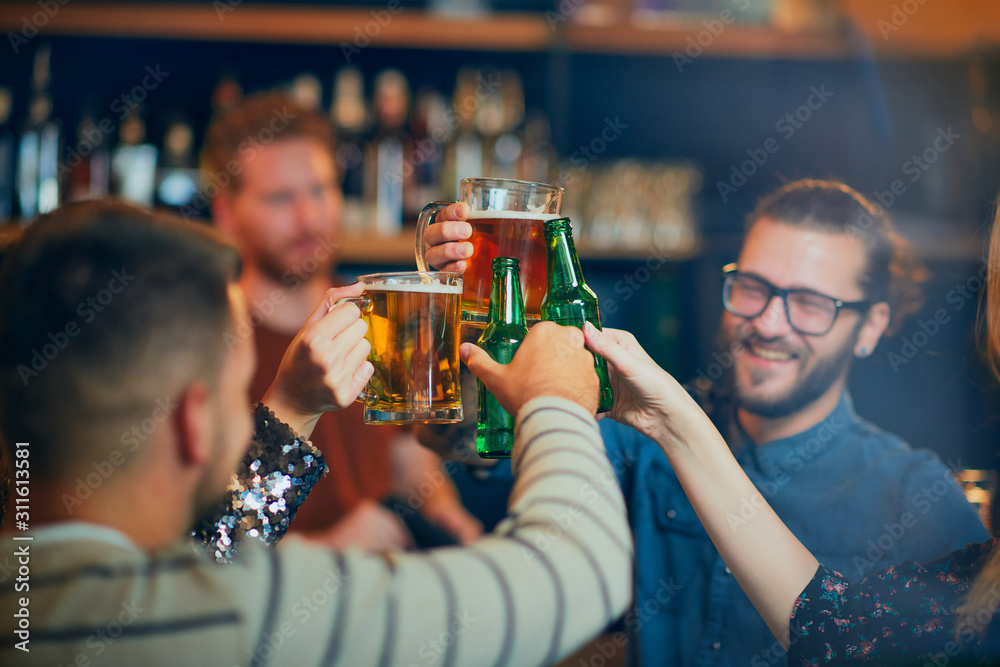 Friends standing in bar and toasting with beer. Friends standing in bar and toasting with beer.