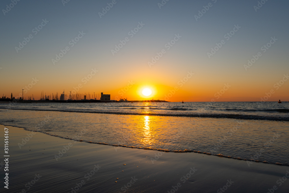 Orange sunset at the beach with golden reflection on the water  and sands, shot at summer night