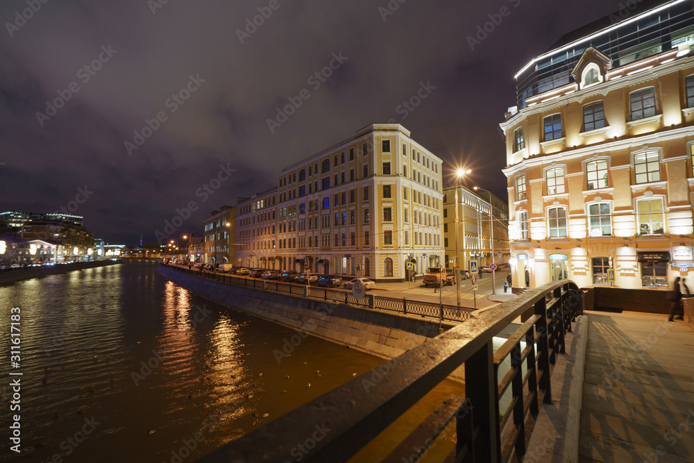 Moscow cityscape in night time. Zverev Bridge is an old pedestrian arch bridge that spans Vodootvodny Canal in Zamoskvorechye district of downtown.