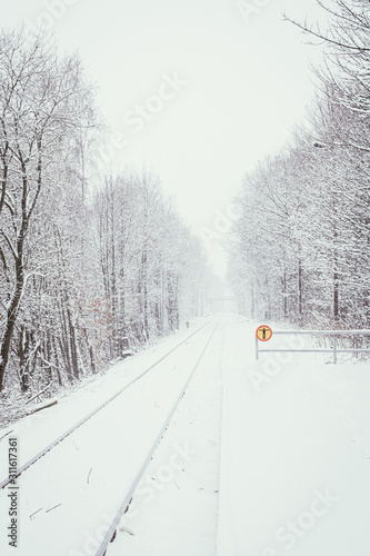 a snowy railway track through a forest