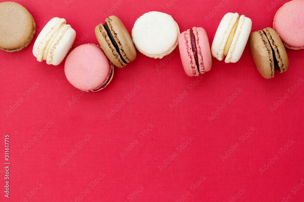 Obraz premium Macarons cakes. Abstract Christmas food photo background with delicious macaroons over red background. Flat lay social media walpaper. Copy space.