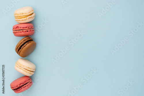 Macarons cakes. Fashion or feminine background delicious macaroons in row on blue background. Flat lay social media walpaper. Copy space. photo