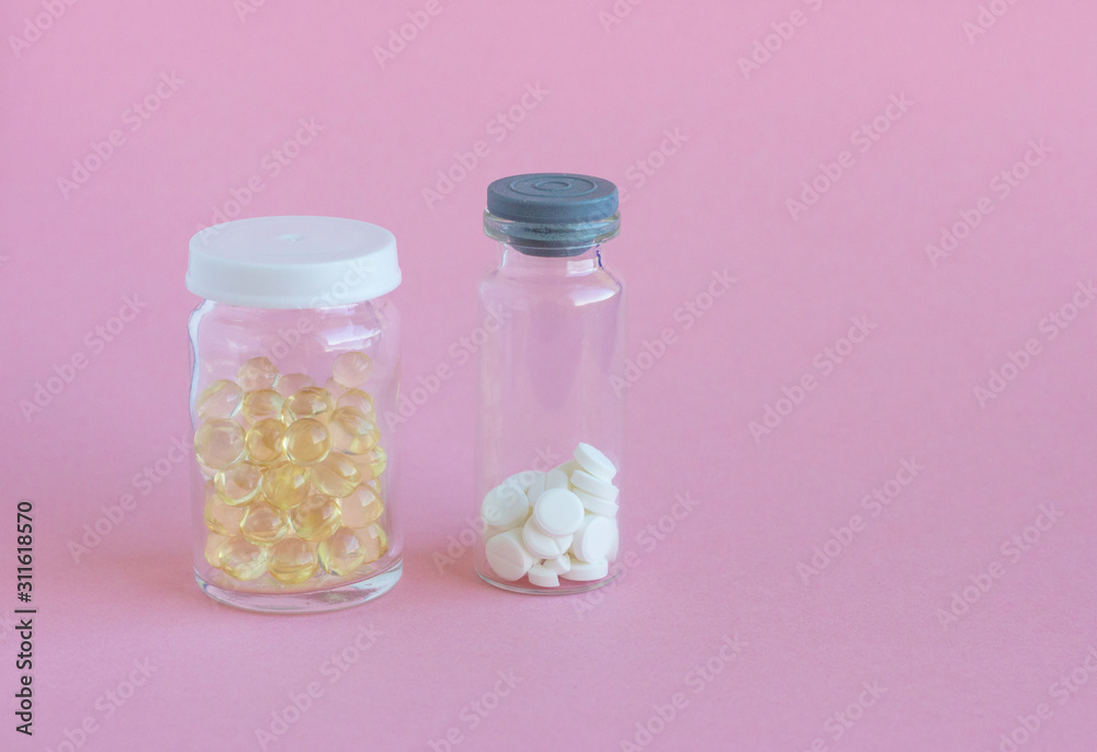 Different medical pills in glass jar on a light pink background with copy space for text. Viral infection season. Traditional medicine, healthcare and wellness concept. Different medical pills in glass jar on a light pink background with copy space for text. Viral infection season. Traditional medicine, healthcare and wellness concept.