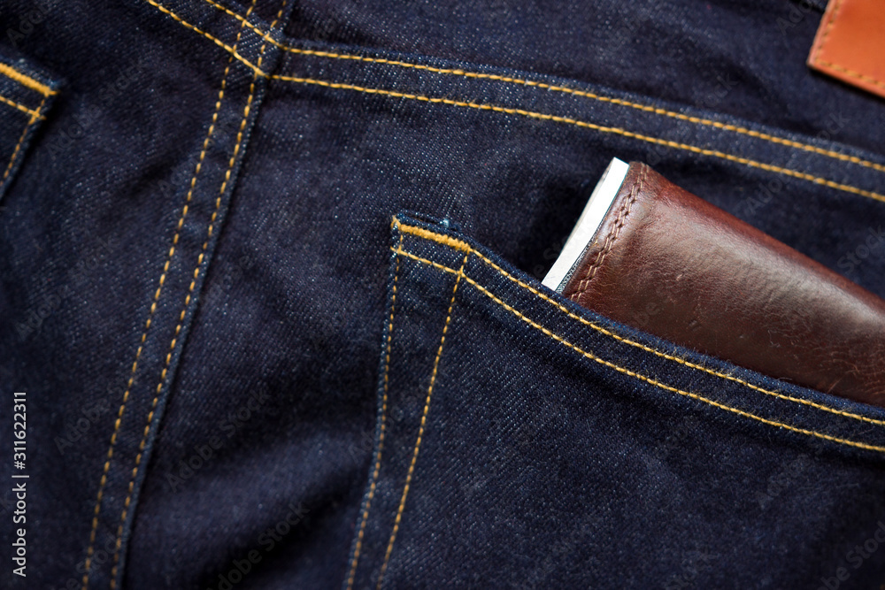 Wallet and usd banknote showing in back pocket of jeans. Selective focus on the edge of the wallet.