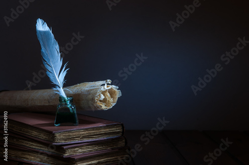 Quill pen and rolled papyrus sheets on a wooden table with old books