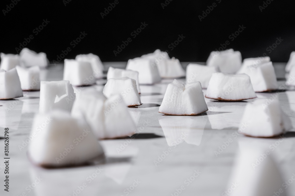 Coconut slices on a black background. Reflection on the marble table. Coconut slices on a black background. Reflection on the marble table.