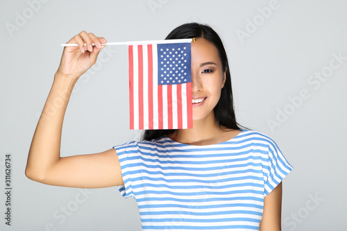 Young woman holding American flag on grey background © 5second