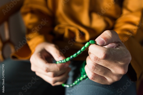 Islamic concept of a muslim guy holding Islamic rosary. Selective focus on rosary with small depth of field, image may contain soft focus.