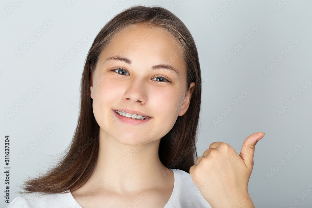 Young girl showing thumb up on grey background Young girl showing thumb up on grey background