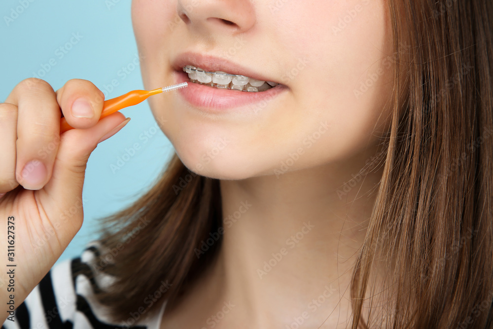 Young girl with dental braces holding toothbrush on blue background Young girl with dental braces holding toothbrush on blue background