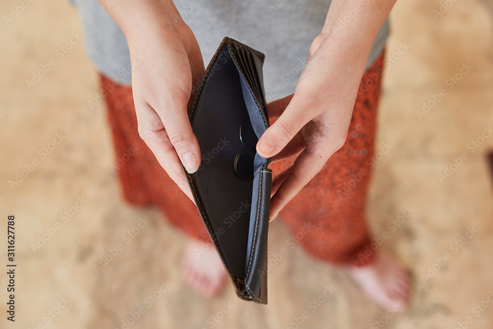 Girl holds an empty wallet in her hands. Bankruptcy concept.