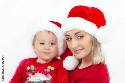 Portrait of mother and daughter in Christmas hats Santa Claus on a white background. Close up. The concept of happy childhood and family happiness.