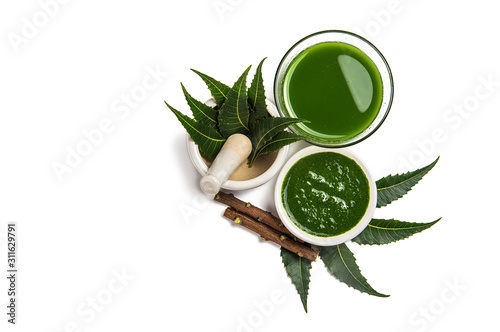 Medicinal Neem leaves in mortar and pestle with neem paste, juice and twigs on white background