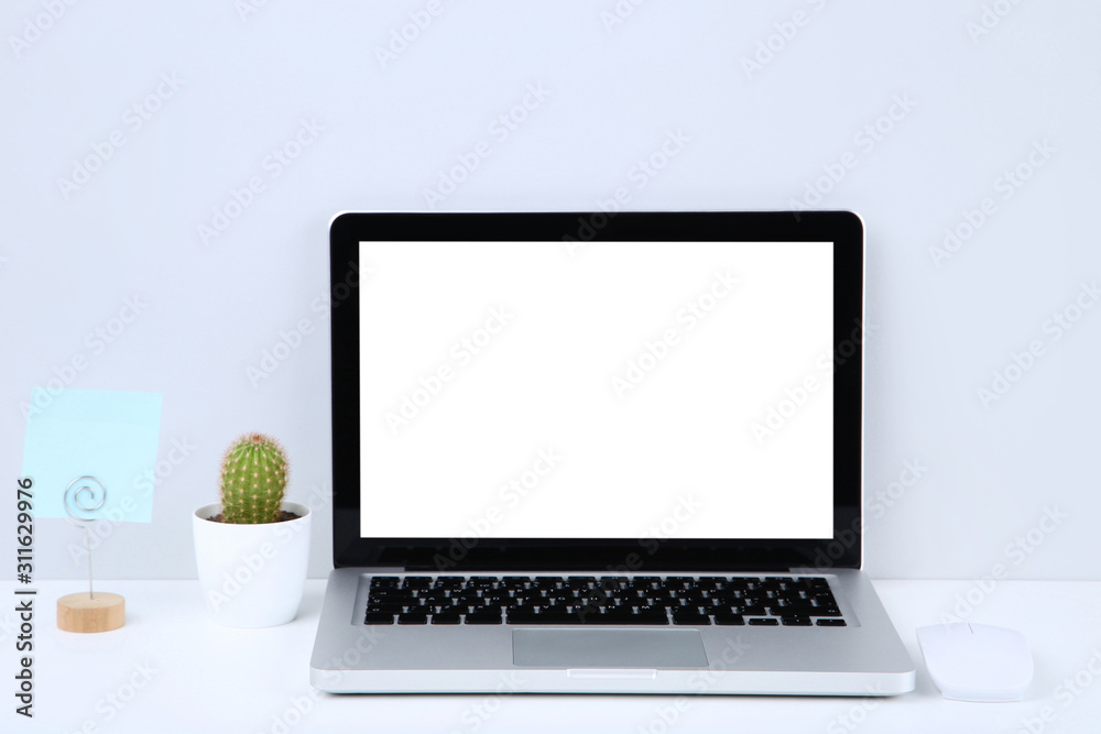 Laptop computer with blank sheet of paper and green cactus on grey background Laptop computer with blank sheet of paper and green cactus on grey background