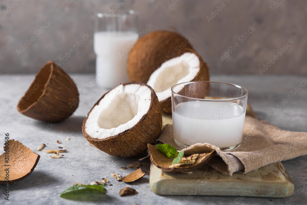 Cracked fresh coconut, milk  and slice nut on concrete background, space for text Food ingredients, healthy lifestyle, paradise concept