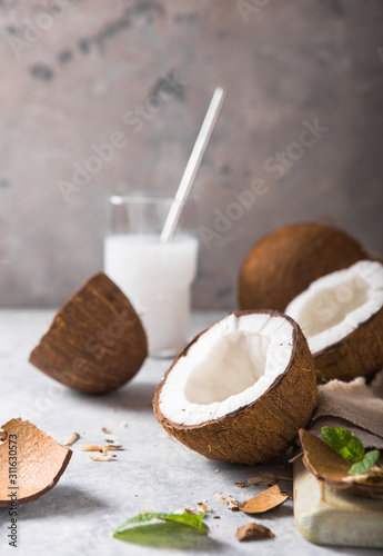 Cracked fresh coconut, milk and slice nut on concrete background, space for text Food ingredients, healthy lifestyle, paradise concept