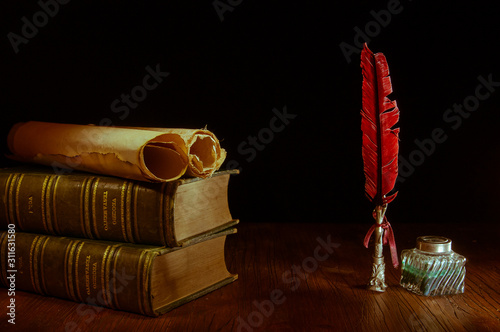 Quill pen and rolled papyrus sheets with old books , warm tone