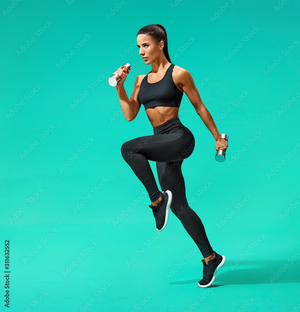 Sporty woman jumping with dumbbells. Photo of active woman in black  sportswear on turquoise background. Dynamic movement. Side view. Sport and  healthy lifestyle Stock Photo | Adobe Stock