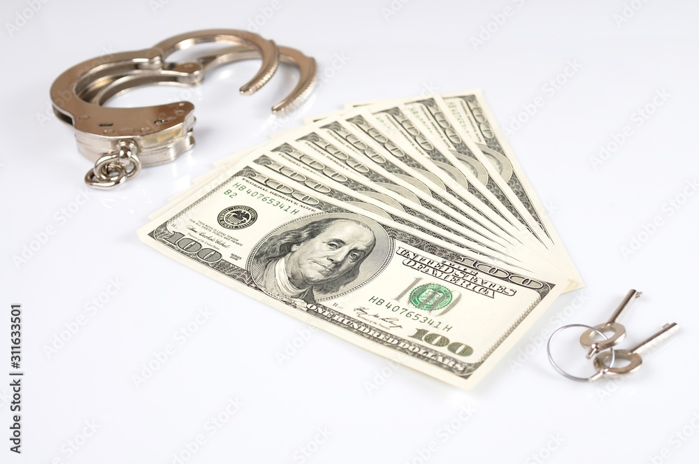 Open metal handcuffs, keys and stack of american dollars cash Open metal handcuffs, keys and stack of american dollars cash