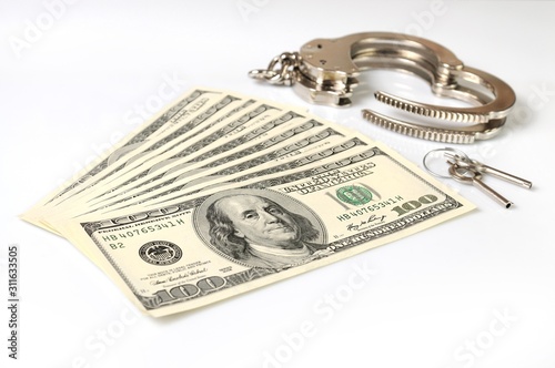 Open metal handcuffs, keys and stack of american dollars cash