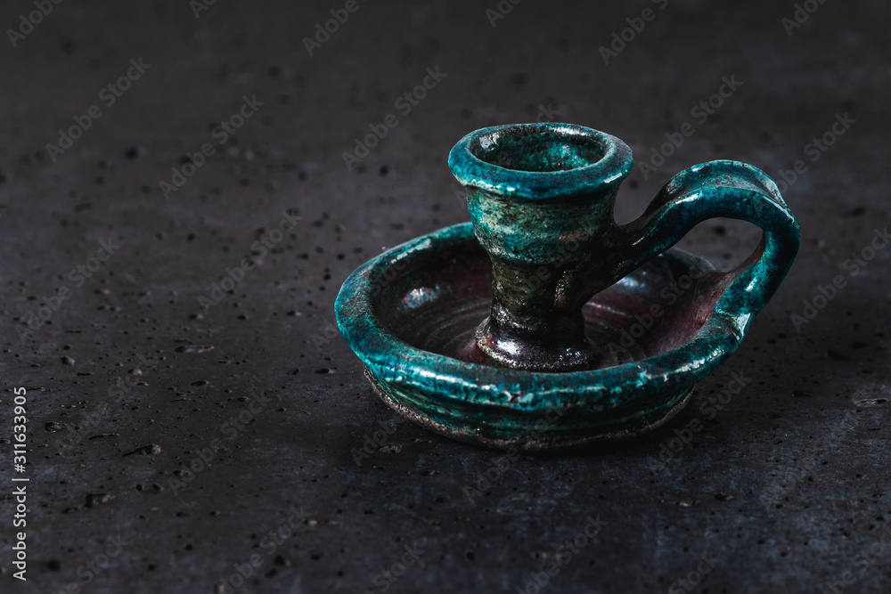 antique ceramic candlestick of turquoise color on gray cement background, ancient object designed for candles representing exquisite home decoration antique ceramic candlestick of turquoise color on gray cement background, ancient object designed for candles representing exquisite home decoration