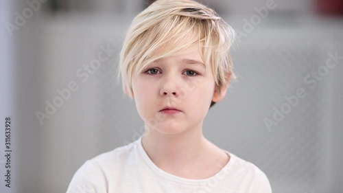 portrait of serious doubted young boy, cute blonde kid photo