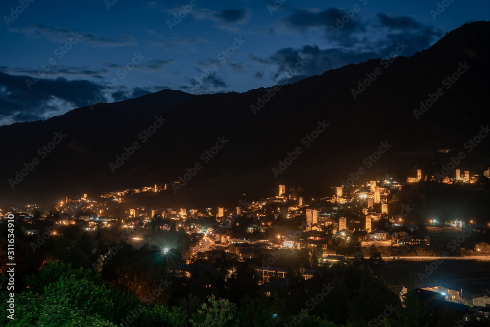 Night view on Mestia with its beautiful illuminated Svan Towers and high mountains. Svaneti, Georgia.