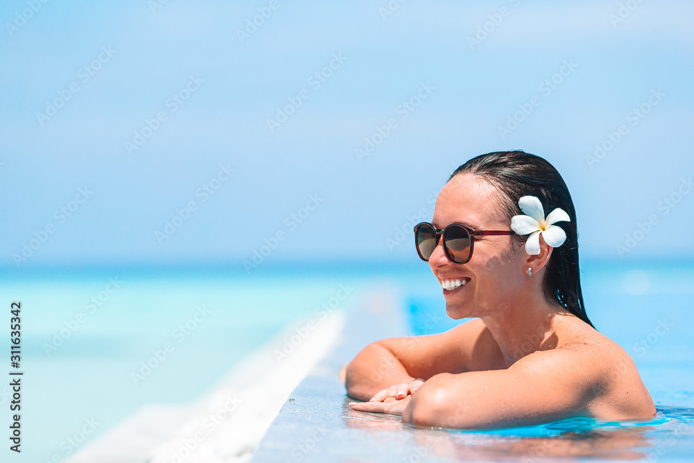Young beautiful woman enjoying summer vacation in luxury swimming pool Young beautiful woman enjoying summer vacation in luxury swimming pool