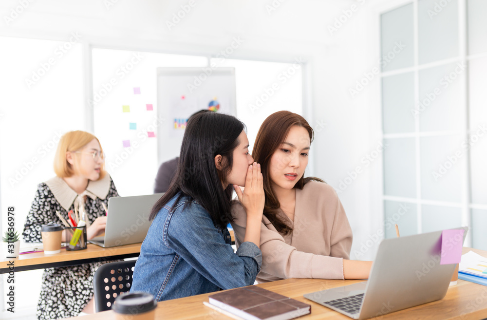 Fototapeta premium couple asian female officer gossip about other officer in workplace, asian female whisper to her friend, poor office activity