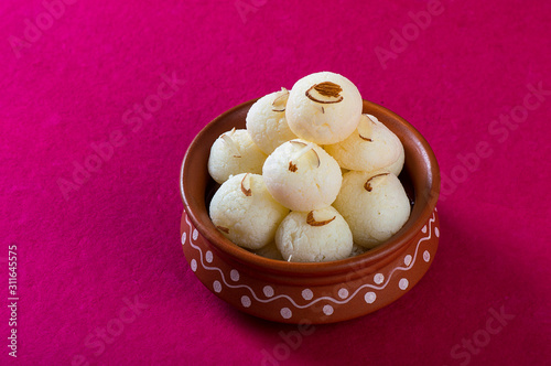 Indian Sweet or Dessert - Rasgulla, Famous Bengali sweet in clay bowl on a pink background. photo