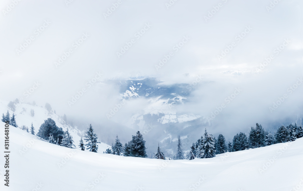 Winter landscape with snow, forest and low clouds in foggy mountains in Zell am See, Austrian Alps Winter landscape with snow, forest and low clouds in foggy mountains in Zell am See, Austrian Alps