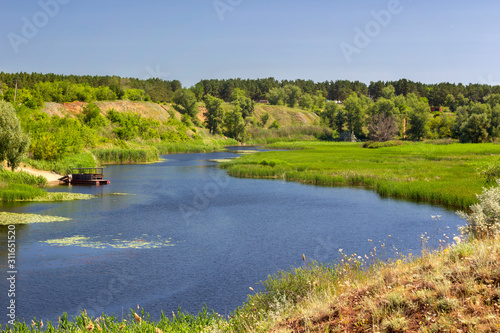 summer landscape, the river meanders and goes into perspective one bank of the river is steep and another gentle, reed thickets, a small pumping station