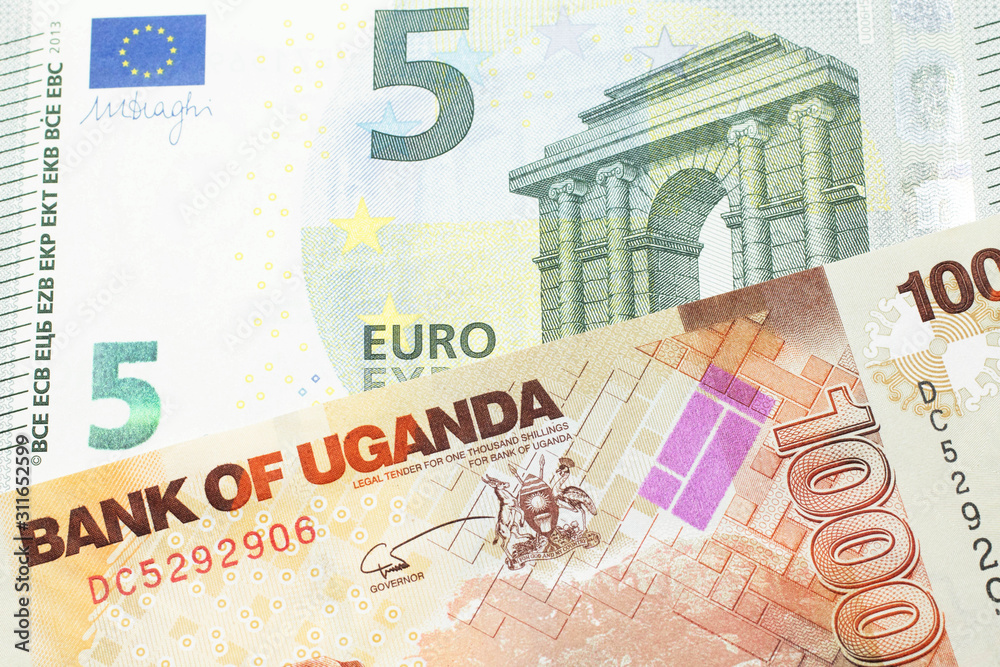 A five euro European bank note with a one thousand Ugandan shilling bill close up in macro A five euro European bank note with a one thousand Ugandan shilling bill close up in macro