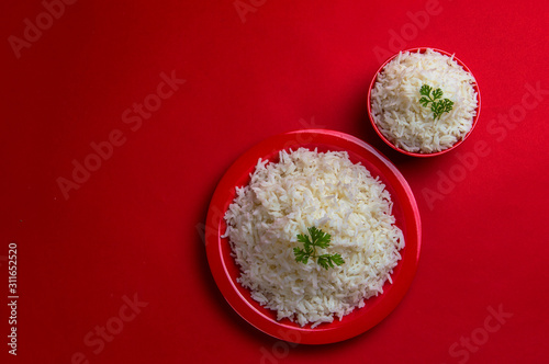 Cooked plain white basmati rice in bowl and plate on red background.