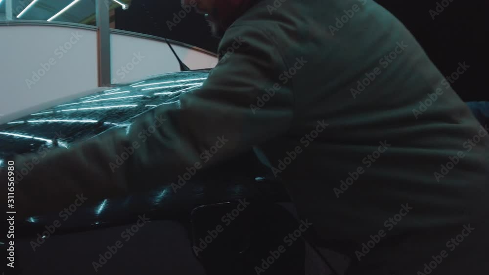 Father and son pushing a car surface with a dry rag outdoor at the evening. Cold weather. Car in foam high resolution. Slow motion Father and son pushing a car surface with a dry rag outdoor at the evening. Cold weather. Car in foam high resolution. Slow motion