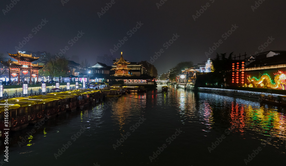 Night scene of Qinhuai River and Fuzimiao from Wende Bridge, with Kuaiguan Pavilion on left bank and Great Spirit Screen on right decorated with dragons, Nanjing, Jiangsu, China.