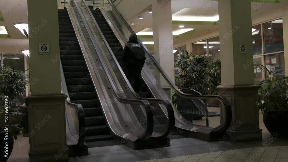 Night shift security guard going up an escalator in a shopping center