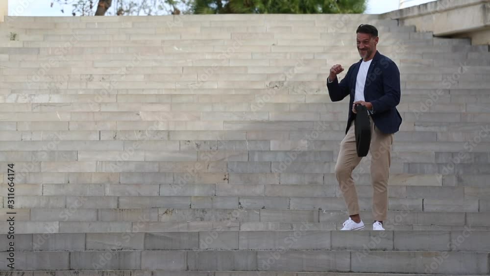 Hombre de mediana edad baila en una escalera contento por una buena noticia