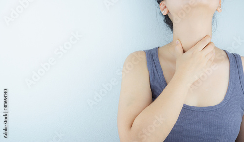 Closeup woman hand touching her neck suffering from sore throat. Health care and medical concept.
