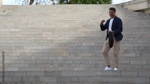 Hombre de mediana edad baila en una escalera contento por una buena noticia photo