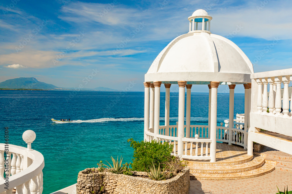 Beautiful white gazebo and tropical flower garden on Caribbean ocean background, summer mountain view , Sosua, Puerto Plata, Dominican Republic Beautiful white gazebo and tropical flower garden on Caribbean ocean background, summer mountain view , Sosua, Puerto Plata, Dominican Republic