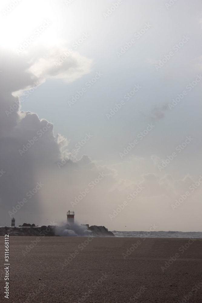 Fototapeta premium Lighthouse with cloudy sunny sky at the beach