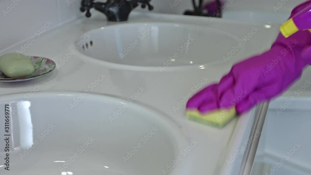 A maid or wife cleans the bathroom sink with rubber gloves. A maid or wife cleans the bathroom sink with rubber gloves.