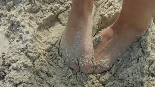 Close-up on the feet of a woman trying to hide them in the beach sand due to athlete's foot or other disease. Slow motion in 4k, UHD